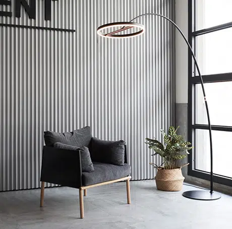 Mur rainuré sombre avec fauteuil noir et lampadaire arc